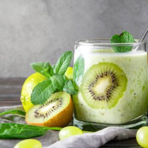 natural yoghurt with fresh kiwi,  spinach, grapes and mint on a grey